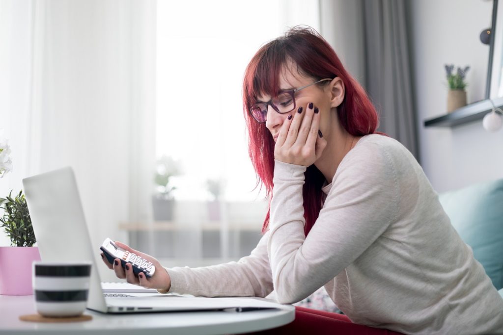 a young woman looking sad with a calculator in hand