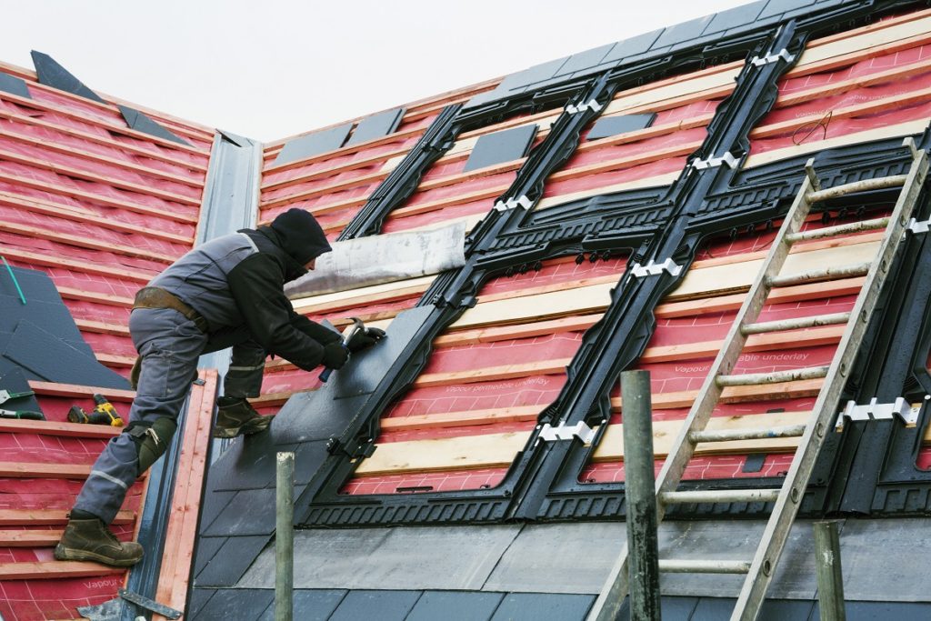 A roofer replacing the tiles on a house roof