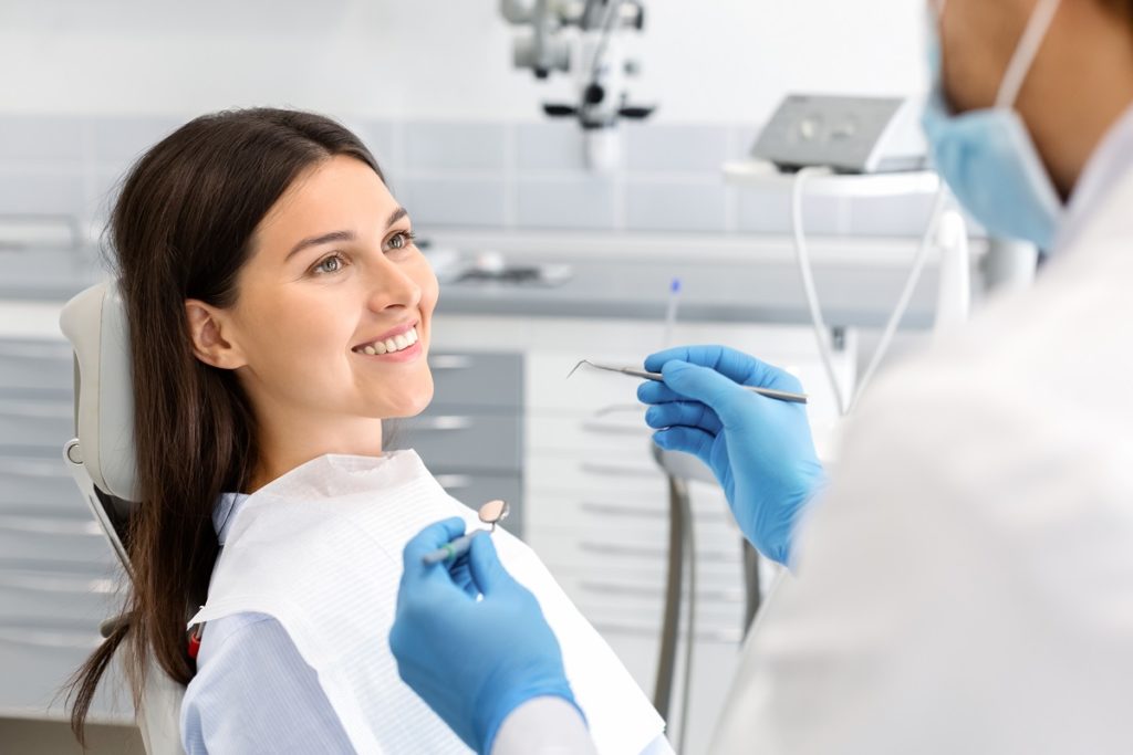 Smiling pretty woman looking at dentist 