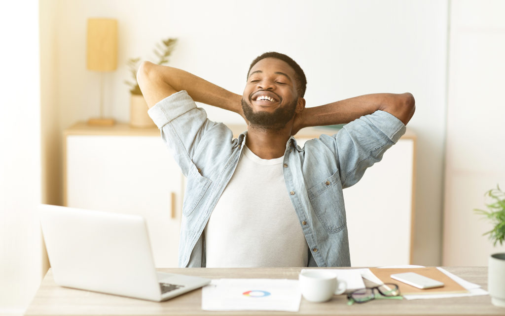 Employee working from home leans back in his chair to stretch